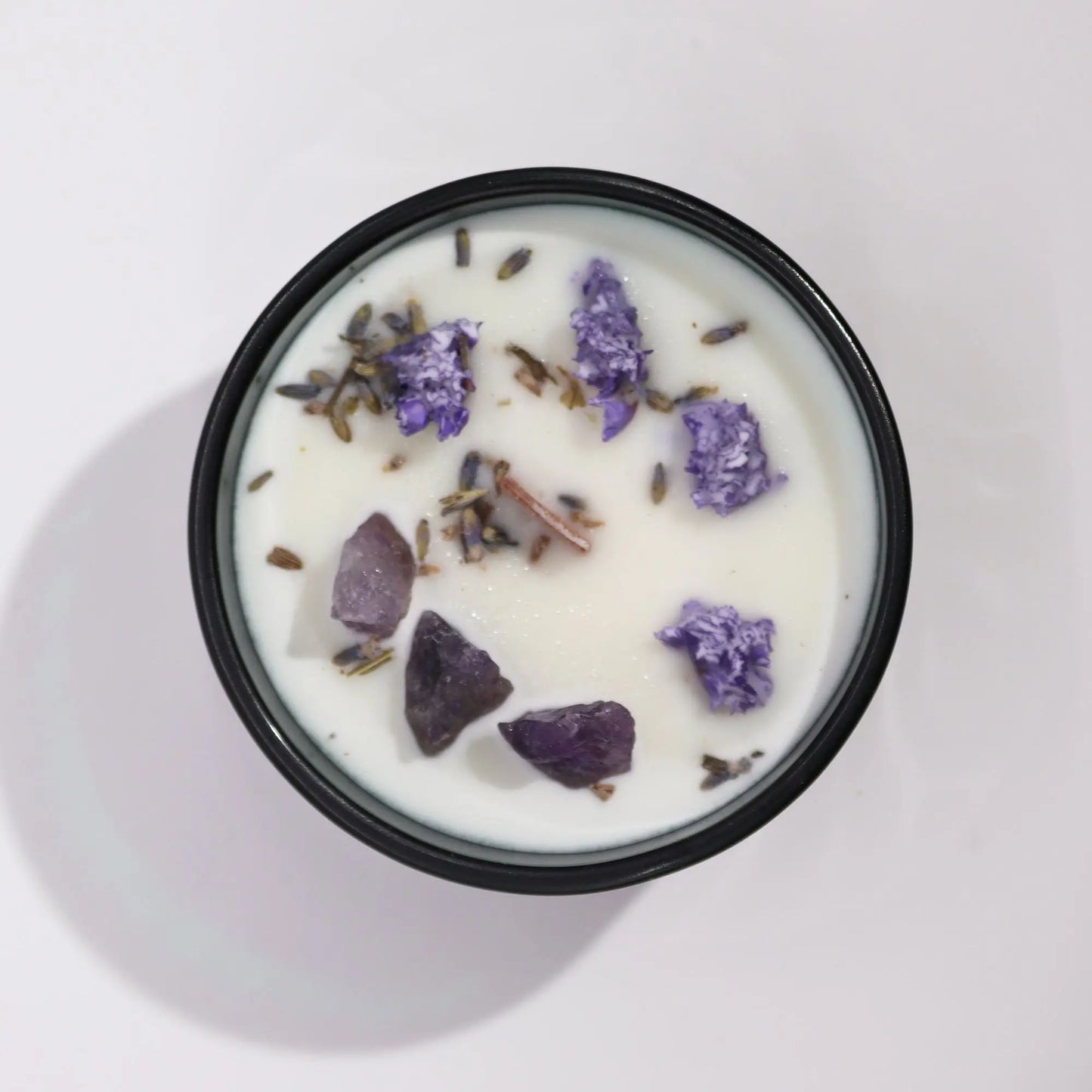 "Hop Hare Crystal Floral Candle overhead view showing amethyst crystals, purple flowers, lavender buds, and cinnamon sticks embedded in white wax"