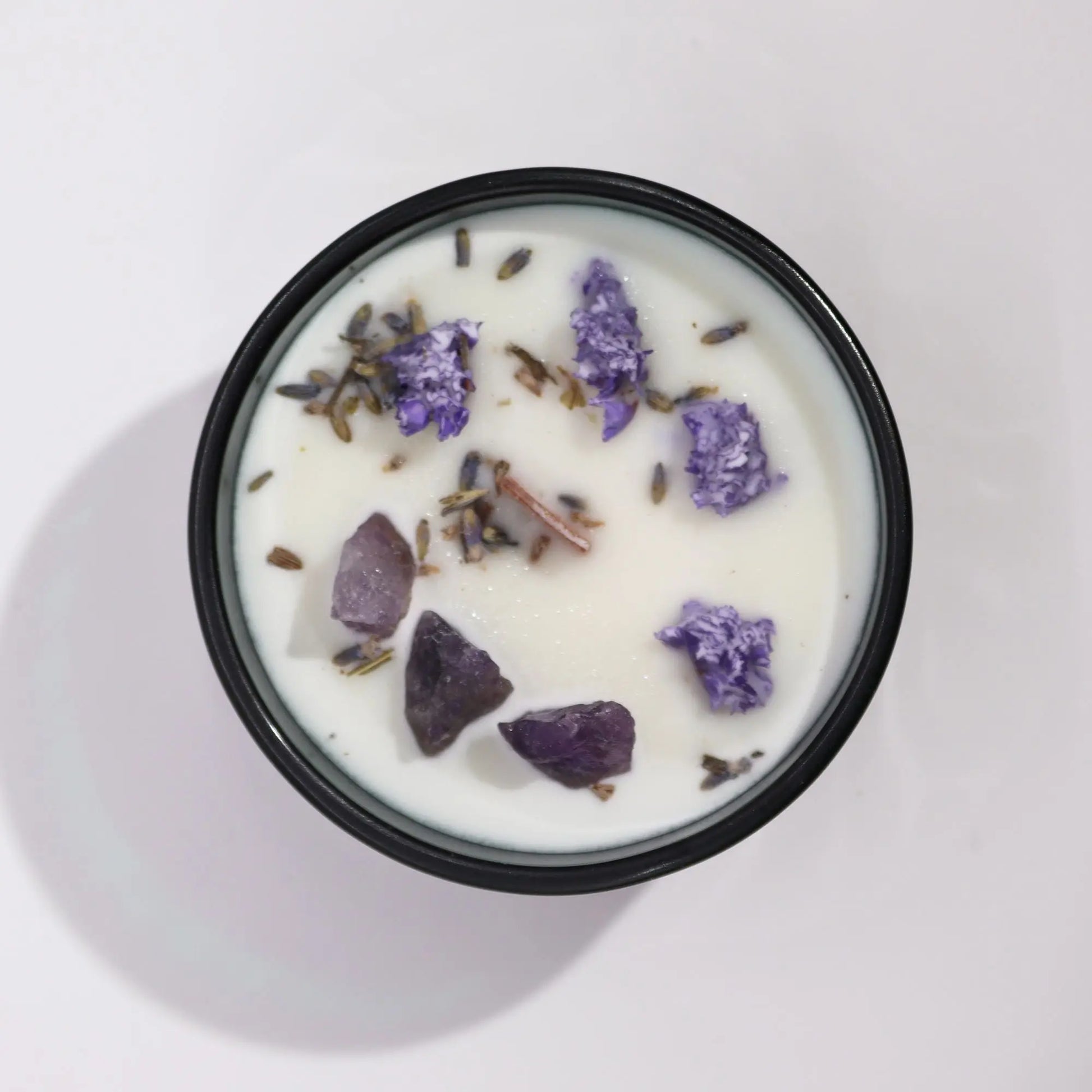 "Hop Hare Crystal Floral Candle overhead view showing amethyst crystals, purple flowers, lavender buds, and cinnamon sticks embedded in white wax"